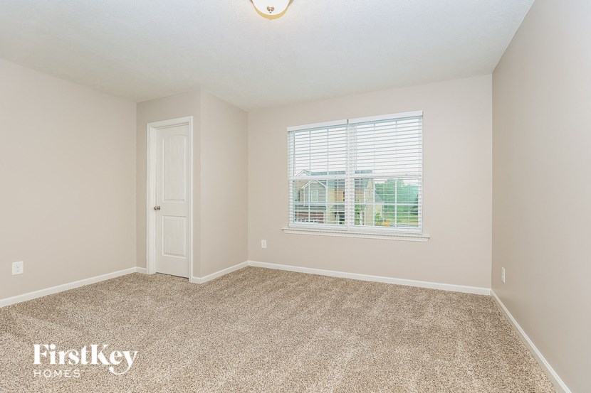 an empty living room with a window and carpet