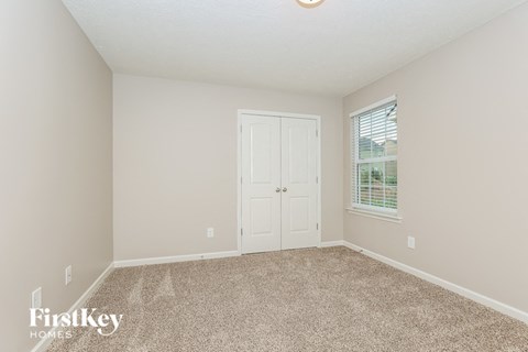 an empty bedroom with a door and a window