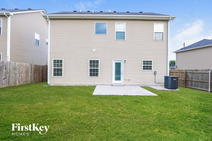 a white house with a yard and a blue backdoor