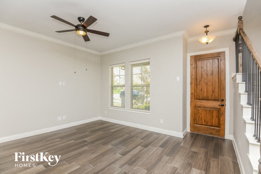 an empty living room with a wooden door and a ceiling fan