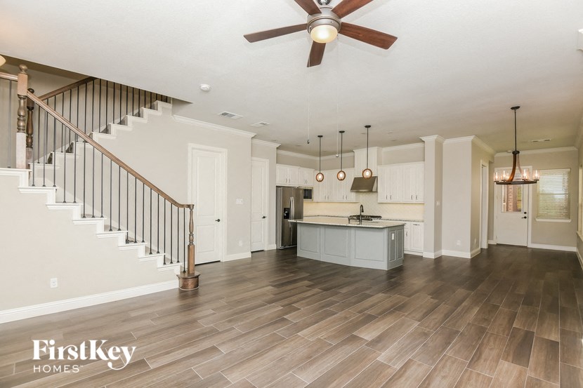 a living room with a kitchen and a ceiling fan