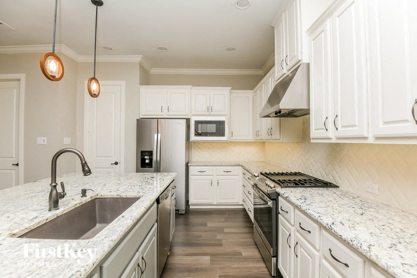 a large kitchen with marble counter tops and white cabinets