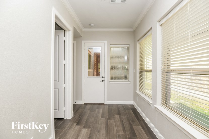 a hallway with a white door and windows with blinds
