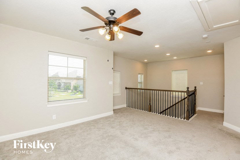 an empty living room with a ceiling fan and a staircase