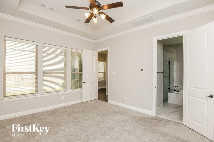 an empty living room with a ceiling fan and a bathroom