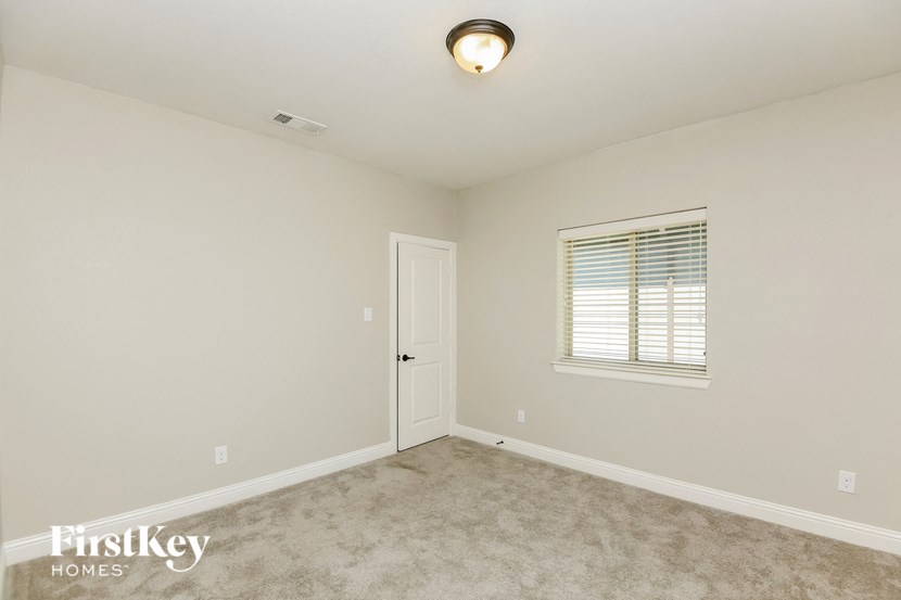 a bedroom with a door and a window and a carpeted floor