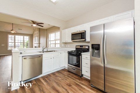 A kitchen with a stainless steel refrigerator, microwave, and oven.