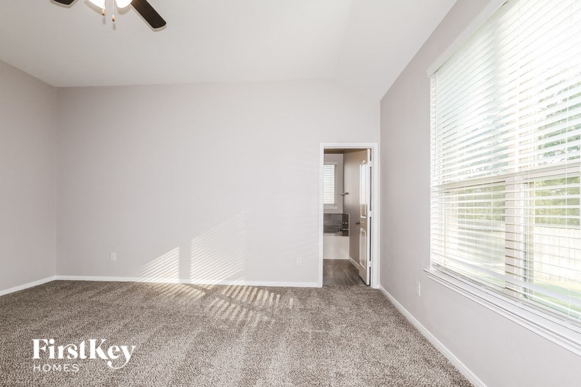 a bedroom with a large window and a carpeted floor