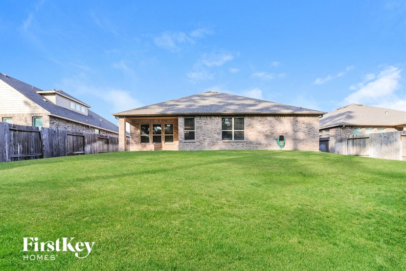 a backyard with a house and a green lawn