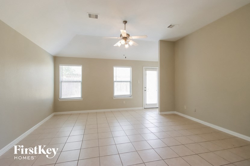 an empty living room with a ceiling fan and tiled floor