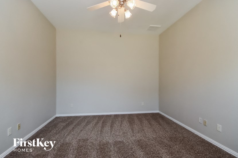 a empty room with carpet and a ceiling fan