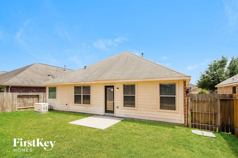 a small tan house with a yard and a fence