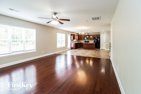 A spacious living room with wood flooring and a ceiling fan.