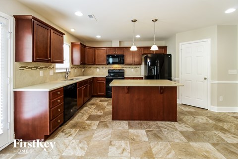 A kitchen with brown cabinets and a black fridge.