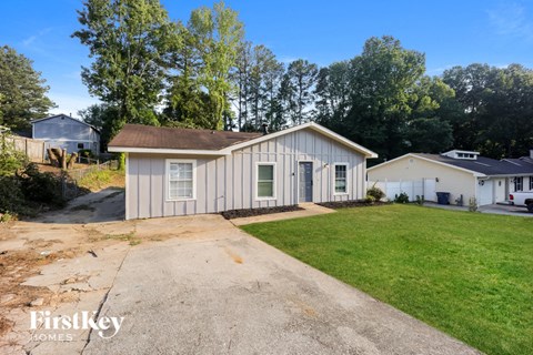 a small white house with a driveway and a grassy yard