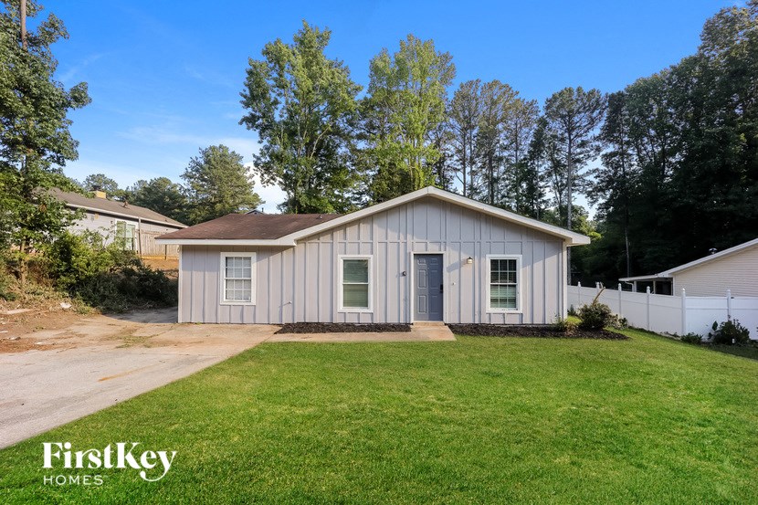 a small white house with a lawn and a driveway