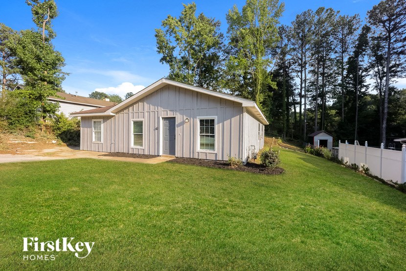 a small gray house on the side of a grassy yard