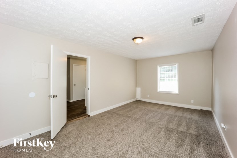 a living room with carpet and a door to a hallway