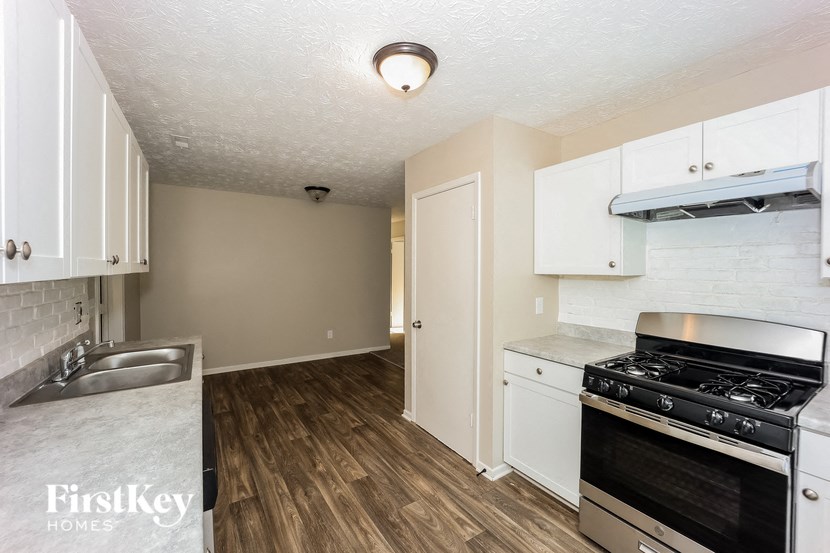 a kitchen with white cabinets and a stove and a sink
