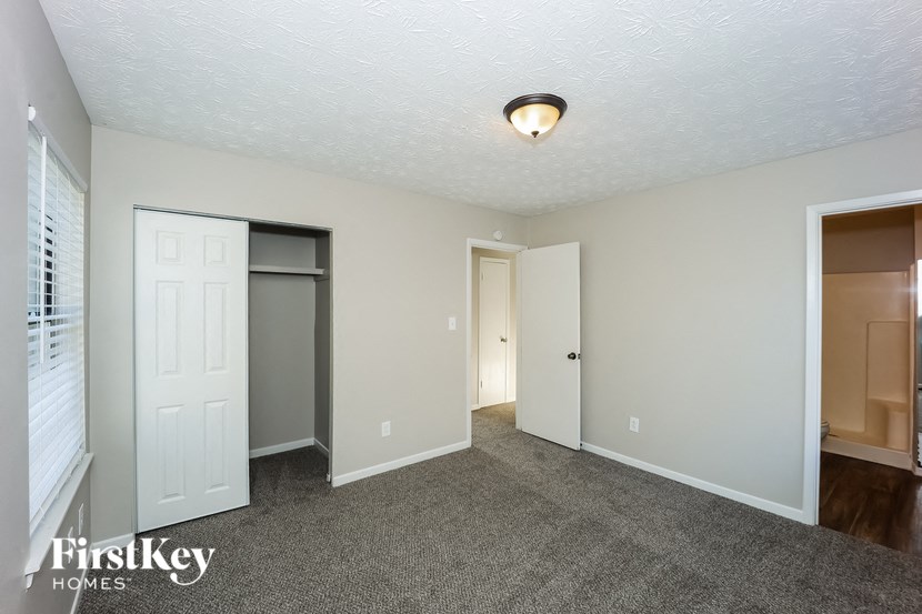 a living room with a carpeted floor and a door to a closet