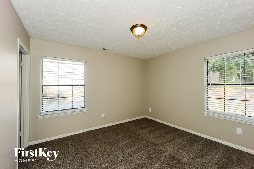 an empty room with carpet and two windows