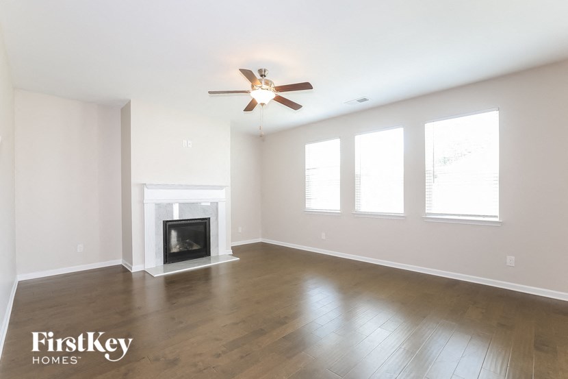 an empty living room with a ceiling fan and a fireplace