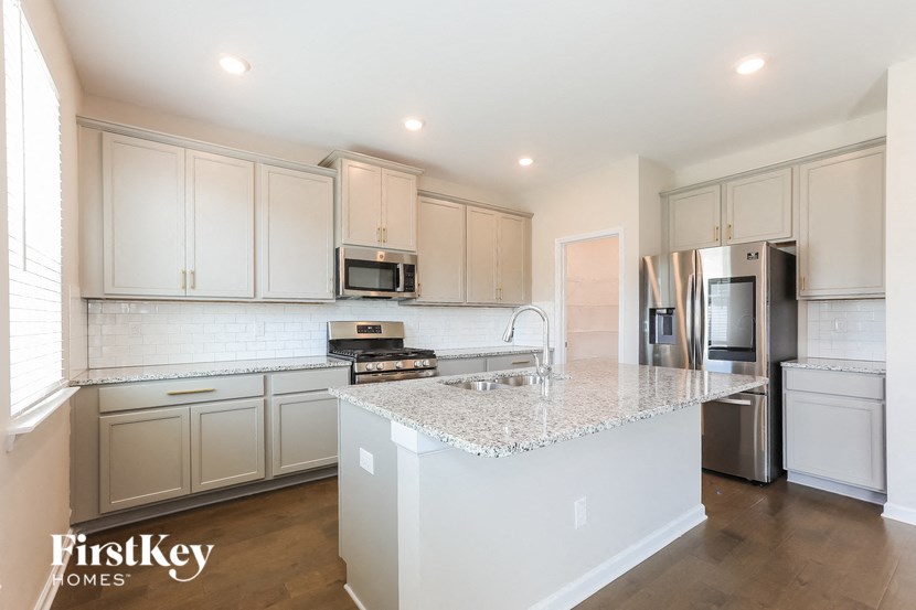 a kitchen with white cabinets and a marble counter top