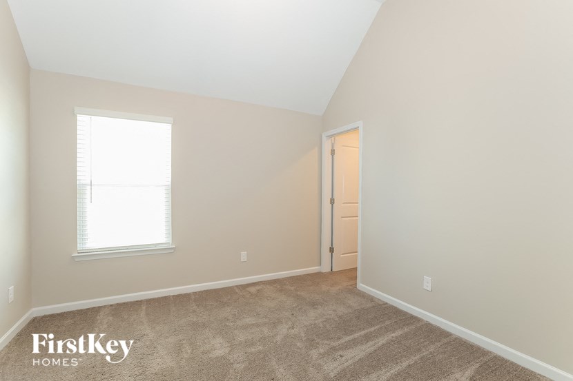 the bedroom of a home with a carpeted floor and a window