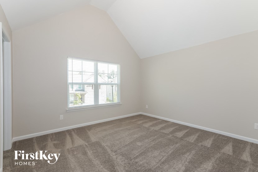 the bedroom of a home with carpet and a window