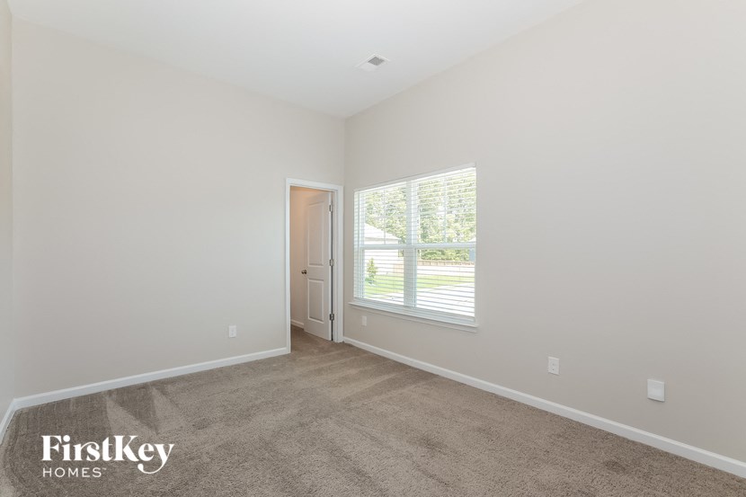 a bedroom with a large window and a carpeted floor