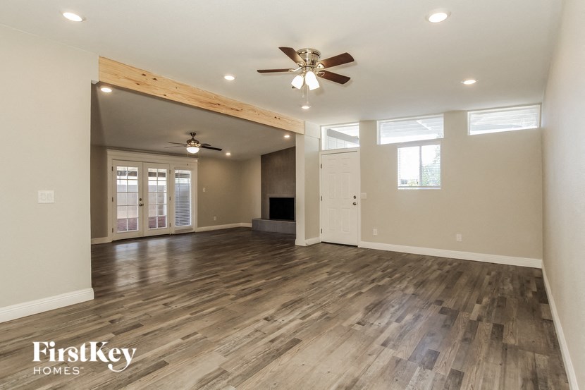 an empty living room with wood floors and a ceiling fan