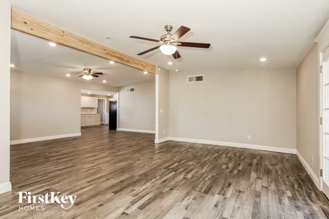 an empty living room with wood flooring and a ceiling fan