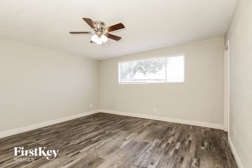 an empty living room with a ceiling fan and a window