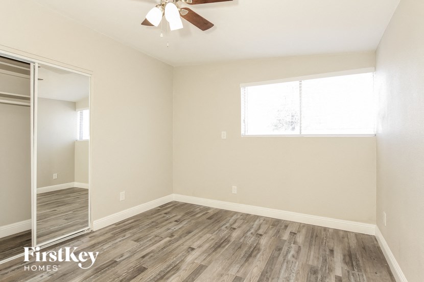 an empty room with wood flooring and a ceiling fan