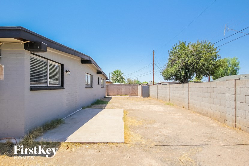 an empty driveway with a white house and a fence