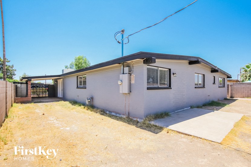 a small white house with a driveway and a gate