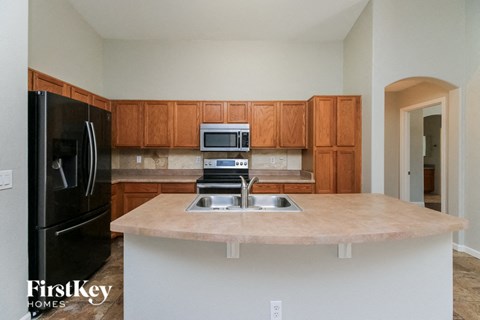 A kitchen with a black fridge, microwave, and stove top oven.