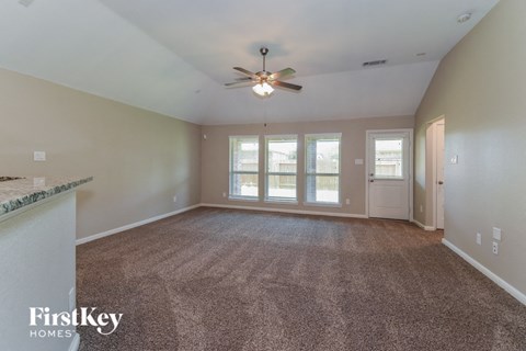 an empty living room with a ceiling fan and a window