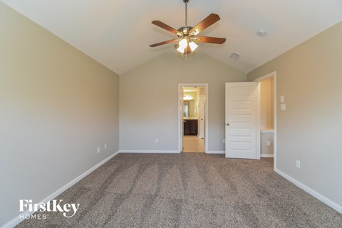 a spacious living room with carpet and a ceiling fan