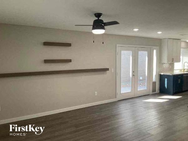 an empty living room with a ceiling fan and a door