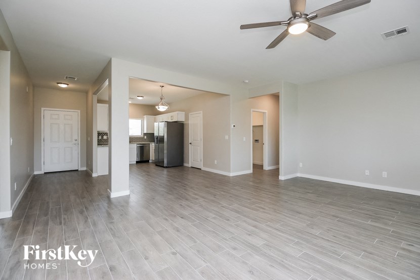 an empty living room and kitchen with a ceiling fan