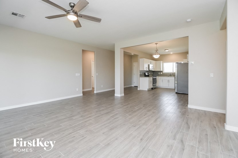an empty living room and kitchen with a ceiling fan