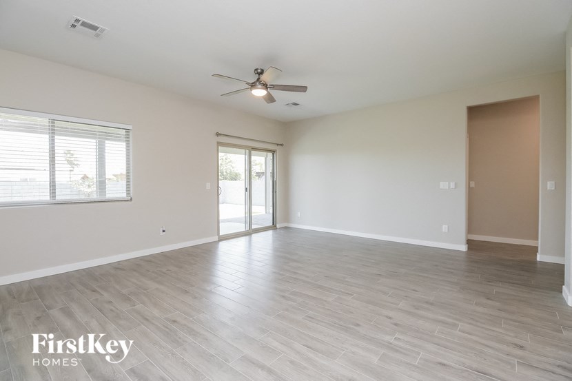 an empty living room with a ceiling fan and a window