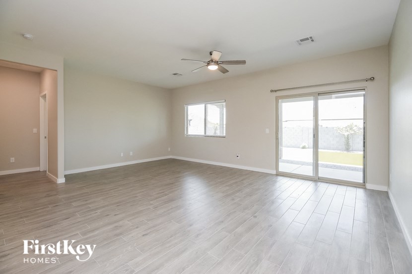 an empty living room with wood floors and a ceiling fan