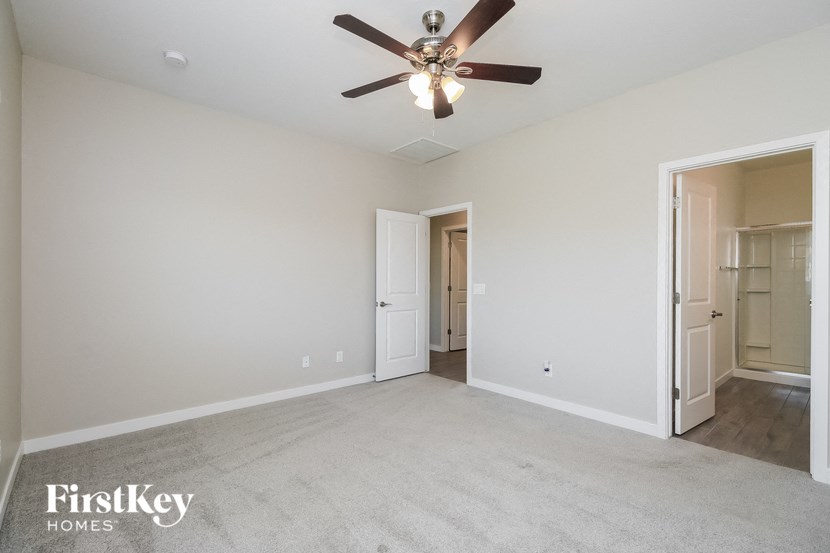 an empty living room with a ceiling fan and a closet