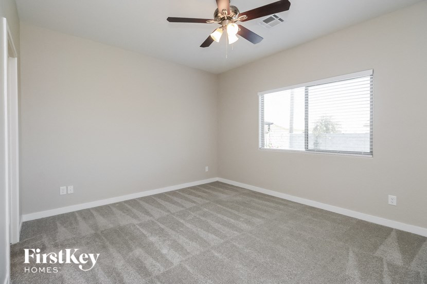 an empty living room with a ceiling fan and a window