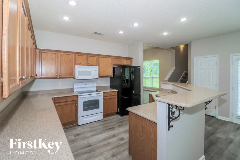 A kitchen with wooden cabinets and a white stove top oven.