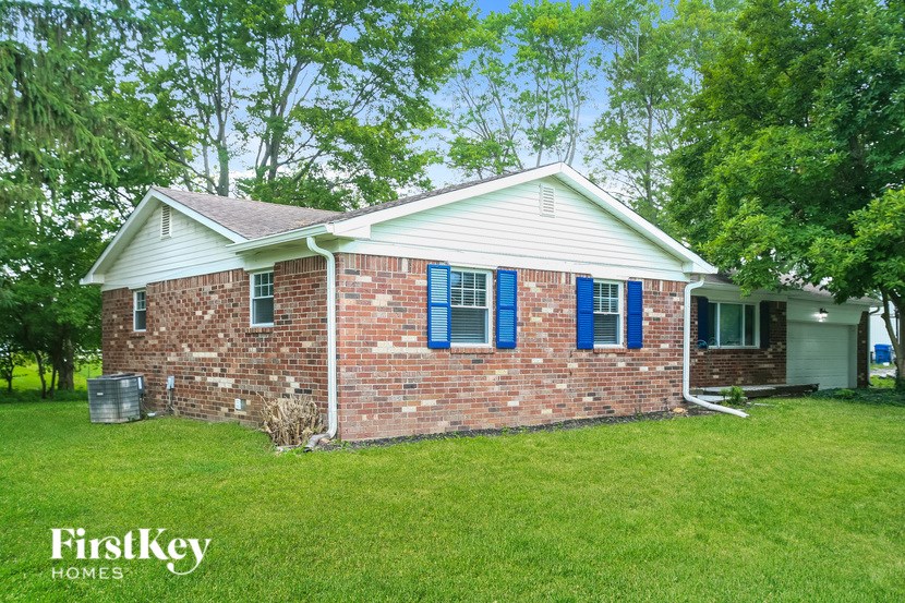 A brick house with a white roof and blue shutters.