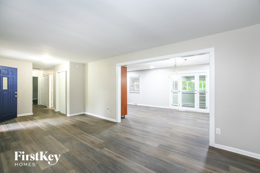 A room with wooden floors and a white door leading to another room.