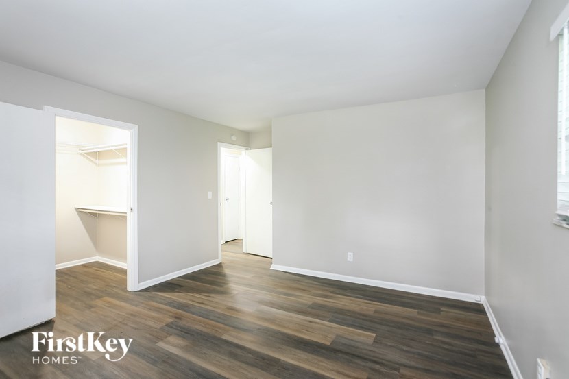 A room with wooden flooring and white walls, with a doorway leading to another room.